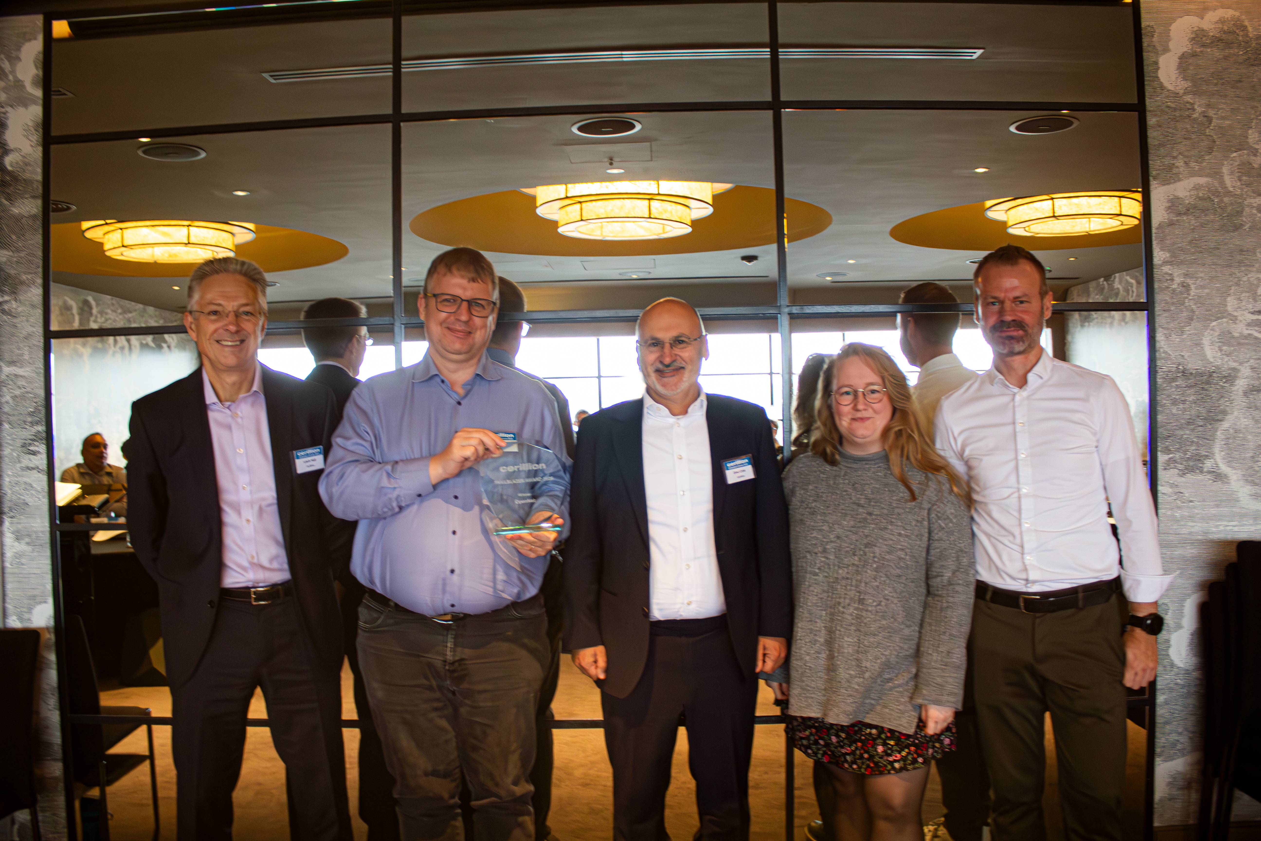 Five people posing for an award, one holding a trophy